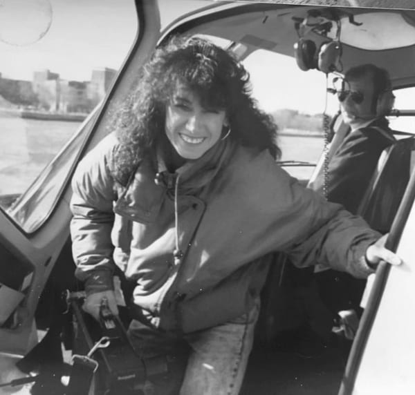 Karen Vitale stepping from a helicopter while carrying camera gear during her earlier production career